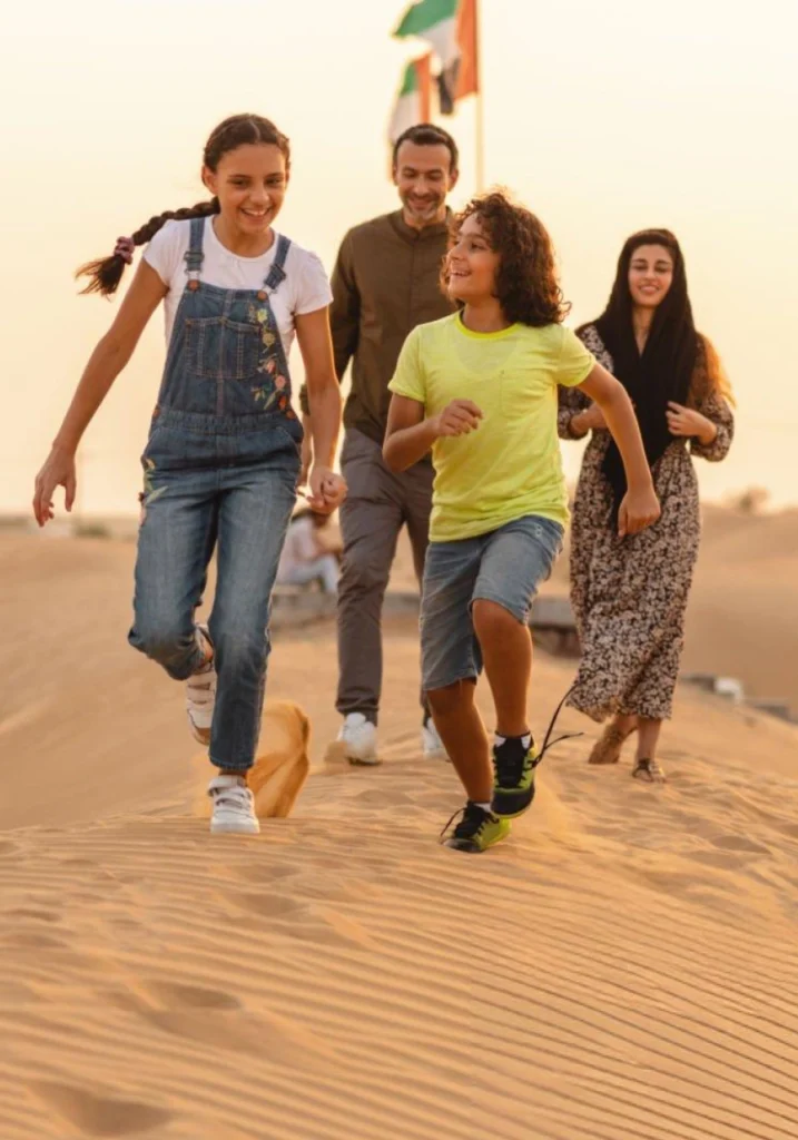 Dubai family vacation — children playing on soft desert dunes during golden hour